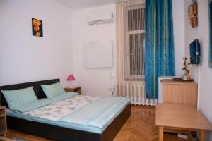 a bedroom with a bed and a window with blue curtains at Vila Crinilor Căciulata in Căciulata