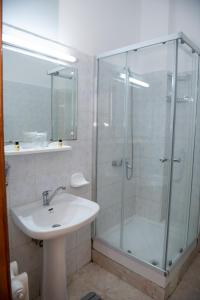 a bathroom with a glass shower and a sink at Vila Crinilor Căciulata in Căciulata