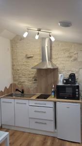 a kitchen with a microwave and a stove top oven at Studio chic meublé et lumineux in Chauray