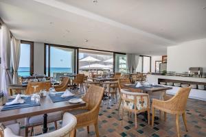 ein Restaurant mit Tischen und Stühlen und dem Meer in der Unterkunft Hoposa Niu in Cala de Sant Vicent