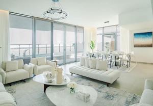 a living room with white couches and tables and windows at Blausee Beachfront Villa with Private Pool in Al Ḩamrīyah