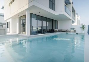 a large swimming pool with a white house at Blausee Beachfront Villa with Private Pool in Al Ḩamrīyah