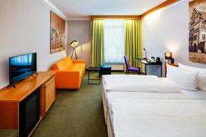 a hotel room with two beds and a flat screen tv at Best Western Parkhotel Brehna-Halle in Brehna