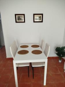 a white dining room table with white chairs at Aires de Chipiona Apartamento A in Chipiona