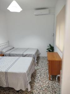a room with two beds and a table and a desk at Aires de Chipiona Apartamento A in Chipiona