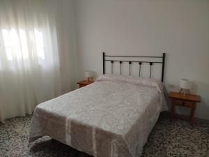 a bedroom with a bed and two tables with lamps at Aires de Chipiona Apartamento A in Chipiona +6 photos