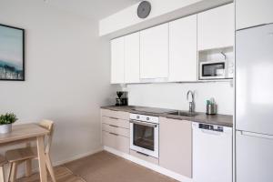 a kitchen with white cabinets and a table at Hiisi Homes Klaukkala in Klaukkala
