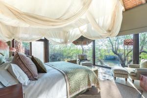 a bedroom with a bed and a large window at Last Word Makanyane in Laastepoort
