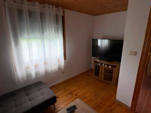 a living room with a flat screen tv and a couch at Cabana do Sil in Forcas