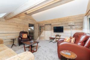 a living room with leather furniture and a flat screen tv at Owl Barn in Little Milton