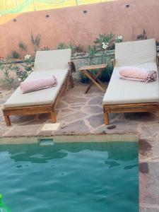 two lounge chairs sitting next to a pool of water at Villa tawarda in Oumnas