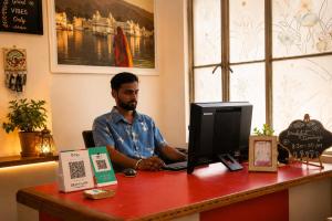 a man sitting at a desk with a computer at Hotel Atithya in Udaipur