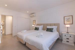 a bedroom with a large white bed with towels on it at Bia in Almancil