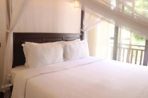 a bedroom with a bed with white pillows and a window at Parrot Perch Villa Dickwella in Dickwella