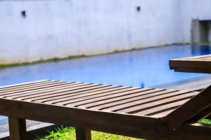 a wooden bench sitting in front of a swimming pool at Parrot Perch Villa Dickwella in Dickwella
