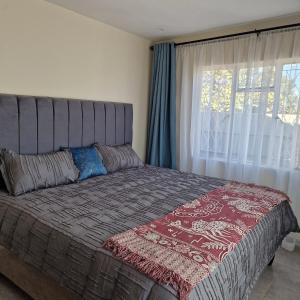 a bed in a bedroom with a large window at Selah House in Harare