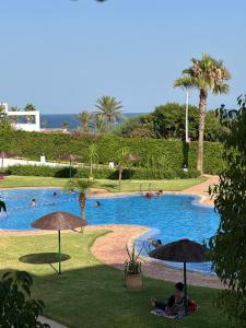 a large swimming pool with people in it with umbrellas at luxury apartament golf the beach capuchino in Cabo Negro