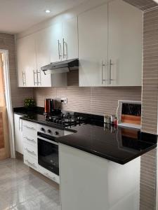 a kitchen with white cabinets and a black counter top at Selah House in Harare