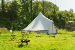 a white tent with a table and chairs in a field at Devon Belltents - Beesands in Kingsbridge