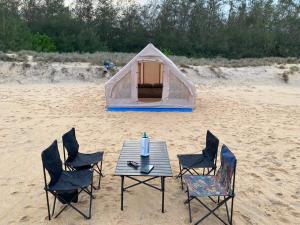 a tent on the beach with a table and chairs at Secret Point Luxury Glamping in Panama