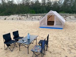 a tent and chairs and a table on a beach at Secret Point Luxury Glamping in Panama