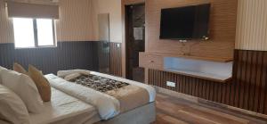 a bedroom with a bed with a television on a wall at Landmark Resort in Sonīpat +7 photos
