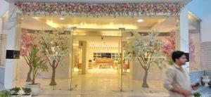 a man walking past a store window with flowering trees at Landmark Resort in Sonīpat