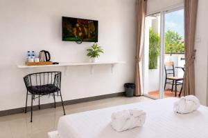 a white room with a bed and a chair at Bliss & Beats Hostel in Phnom Penh