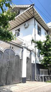 a white building with a fence in front of it at Elegance Hotel Osh in Osh