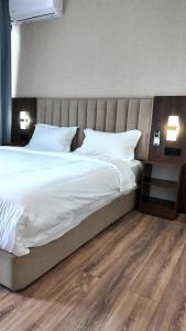 a bedroom with a large bed with white sheets and pillows at Elegance Hotel Osh in Osh