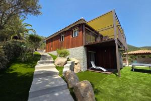 a house with a balcony and a bench in the yard at CASA FUNTA - villa T5 - vue mer- piscine in Sainte-Lucie de Porto-Vecchio