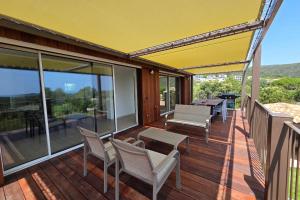 a wooden deck with chairs and a yellow umbrella at CASA FUNTA - villa T5 - vue mer- piscine in Sainte-Lucie de Porto-Vecchio