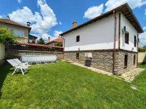 a backyard with a white building and a lawn at Guesthouse Dryanovo in Dryanovo