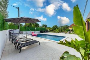 a pool with lounge chairs and an umbrella at Villa Sunshine in Pridraga