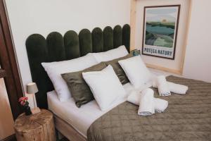 a large bed with white pillows and a green headboard at Domki & Jacuzzi w Centrum Soliny 885-053-839 in Solina