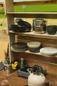 a shelf with plates and pots and pans on it at Devon Belltents - South Milton in Hope Cove