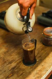 a person pouring coffee into a cup on a table at Devon Belltents - South Milton in Hope Cove