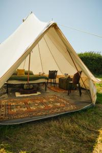a tent with chairs and a couch in a field at Devon Belltents - South Milton in Hope Cove