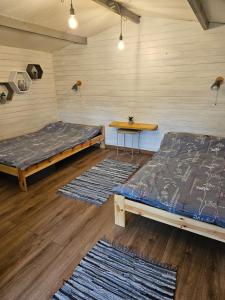 two beds and a table in a room with rugs at Cozy house for your holidays in Bernāti