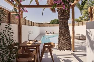a patio with a table and a tree next to a pool at Dionysos Beach Resort & Villas in Mylopotas