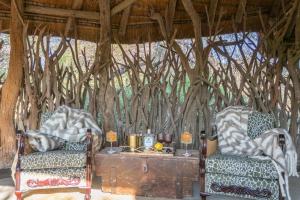 two chairs and a table in a room with trees at Last Word Makanyane in Laastepoort