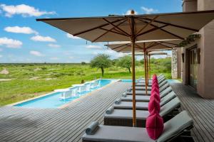 a deck with chairs and an umbrella and a pool at Onguma The Fort in Namutoni Gate