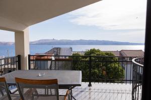 a table and chairs on a balcony with a view of the water at Apartments ANA Karlobag in Karlobag