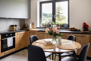 a kitchen with a table with a vase of flowers on it at Cozy mountain house - Coolówka pod Babią Górą in Zubrzyca Dolna