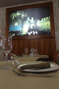 uma mesa com copos de vinho e uma televisão num restaurante em Hotel El Castillo em Ponferrada