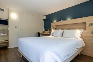 a bedroom with a large white bed with a blue wall at Kyriad Digne-Les-Bains in Digne-les-Bains