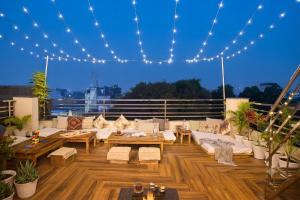 a rooftop patio with white couches and tables and lights at 3 Raahi Varanasi in Varanasi