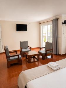 a bedroom with two chairs and a tv on the wall at Hôtel Sofia Bellevue in Antsohihy