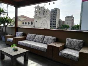 ein Sofa und zwei Stühle auf einem Balkon mit einem Gebäude in der Unterkunft Lima Wasi Hotel Miraflores in Lima