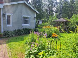 a garden in front of a house with flowers at Peaceful riverside cottage with sauna in Myllykylä +35 photos